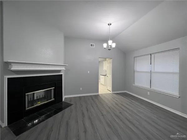 a view of an empty room with wooden floor fireplace and a window