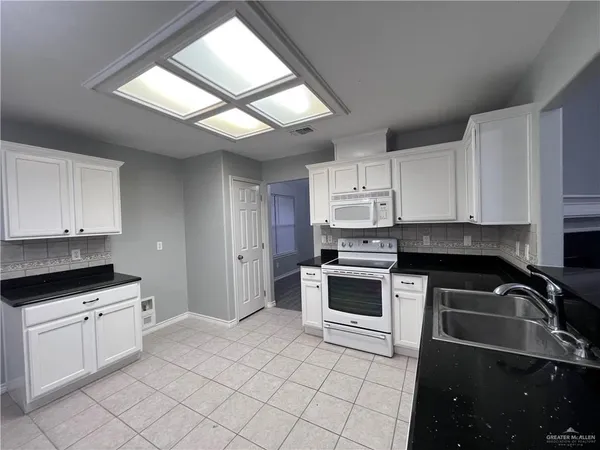a kitchen with granite countertop a stove sink and cabinets