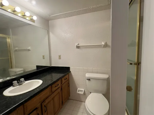 a bathroom with a granite countertop sink toilet and a mirror