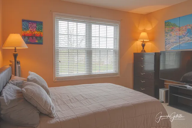 a bedroom with a bed and a lamp next to a window