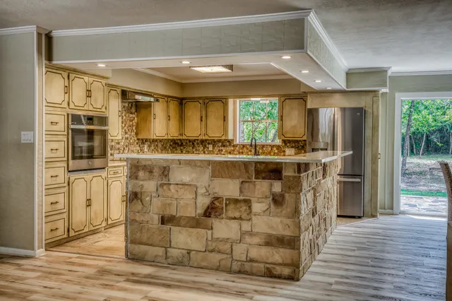 a kitchen with stainless steel appliances kitchen island granite countertop a refrigerator and a stove