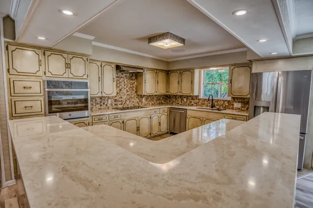 a large kitchen with stainless steel appliances a large counter top