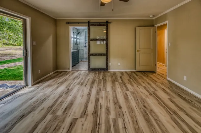 a view of empty room with wooden floor and fan