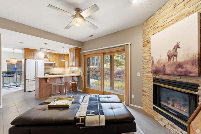 7930 Mustang Loop Road Park City, UT 84098 - Photo 6 of 23 Living room featuring ceiling fan, a stone fireplace, and light tile patterned floors