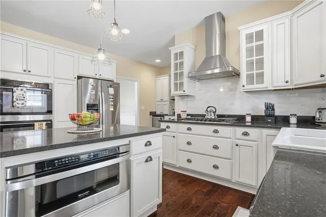 a kitchen with stainless steel appliances granite countertop a stove a sink and white cabinets