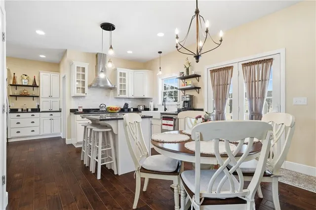a dining room with stainless steel appliances kitchen island granite countertop a table chairs and a living room view