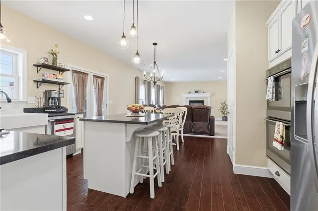 a kitchen with stainless steel appliances kitchen island granite countertop a table chairs and a refrigerator