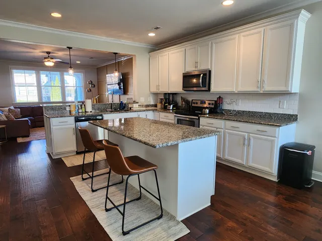 a kitchen with granite countertop a stove top oven a sink dishwasher a dining table and chairs with wooden floor