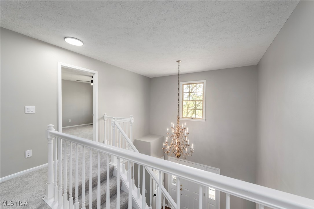 8080 Fair Road Strongsville, OH 44149 - Photo 23 of 50 Corridor featuring an upstairs landing, carpet flooring, baseboards, a textured ceiling, and a chandelier
