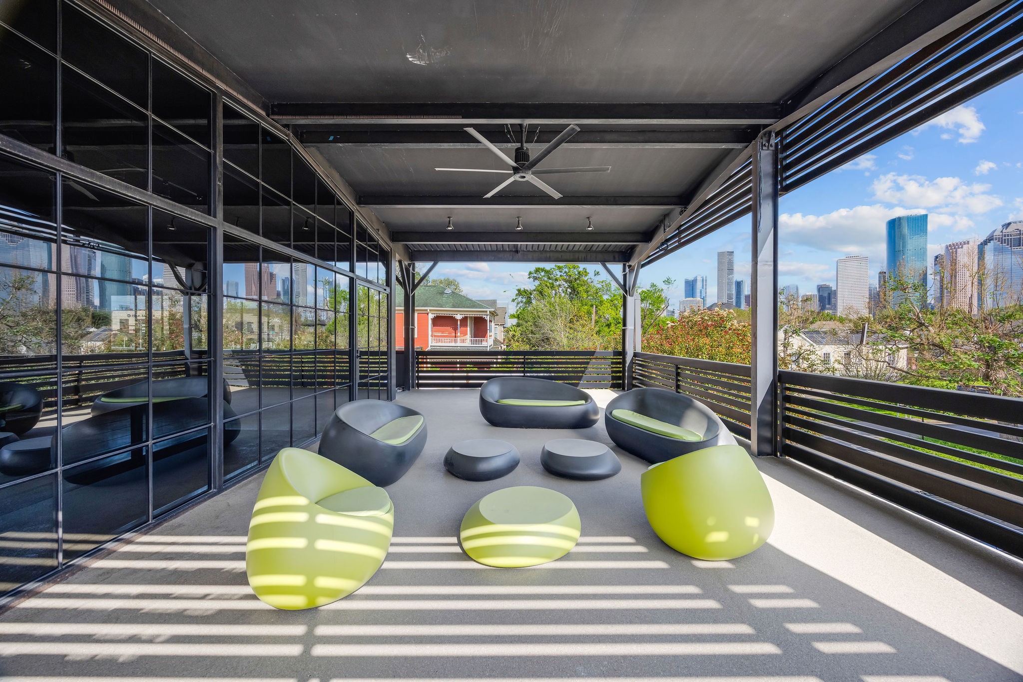 Expansive covered rooftop terrace with ceiling fan, open-air design, and unobstructed views of the Downtown Houston skyline.