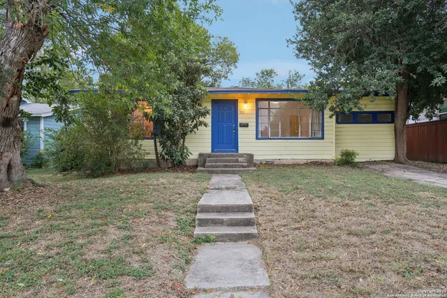 a front view of a house with yard and tree