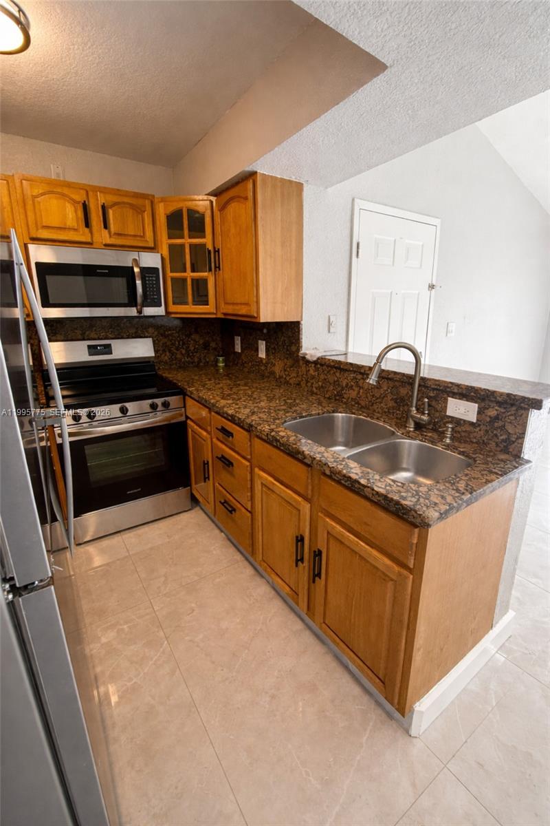 10581 Southwest 155th Court, Unit 1222 Miami, FL 33196 - Photo 4 of 15 a kitchen with stainless steel appliances granite countertop a stove a sink and a microwave
