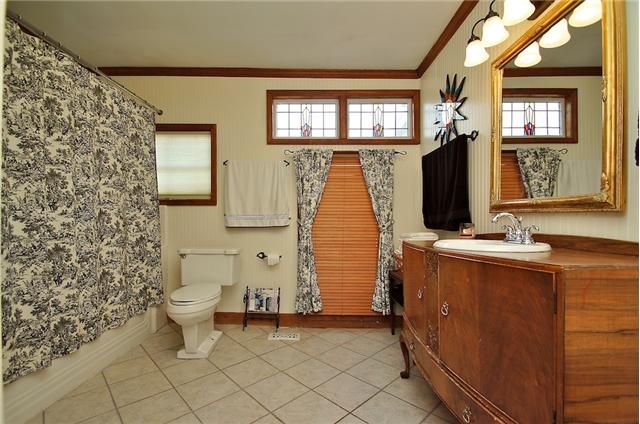 Full bath with vinyl flooring and antique vanity. Beautiful stained glass window. 