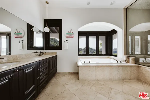 a spacious bathroom with a tub sink and mirror
