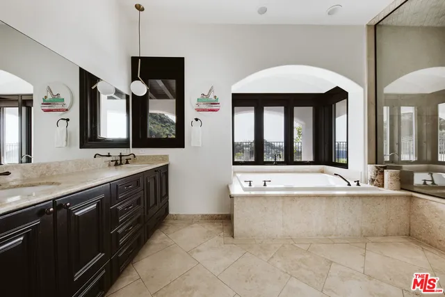 a spacious bathroom with a tub sink and mirror