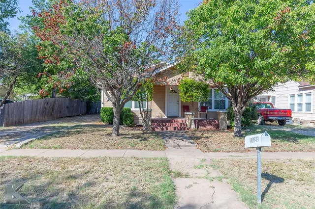 a backyard of a house with table and chairs a barbeque and fence