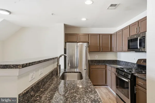 a kitchen with stainless steel appliances granite countertop a stove a sink and a refrigerator