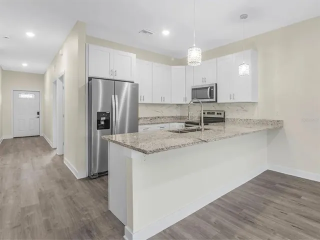 a kitchen with stainless steel appliances granite countertop a refrigerator and a stove top oven