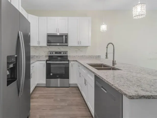 a kitchen with granite countertop a sink stove and refrigerator