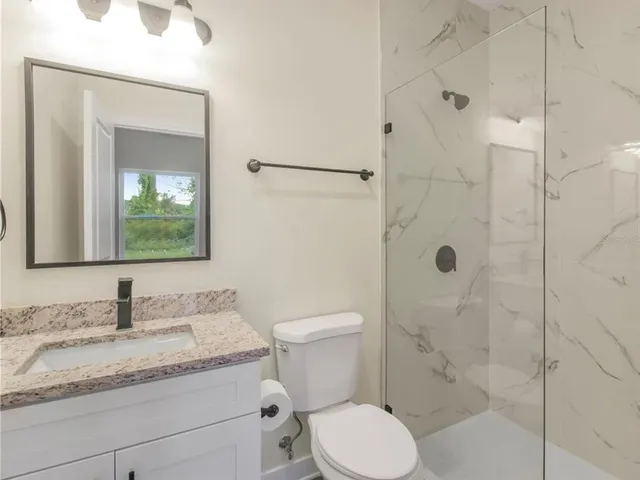 a bathroom with a granite countertop sink toilet and shower