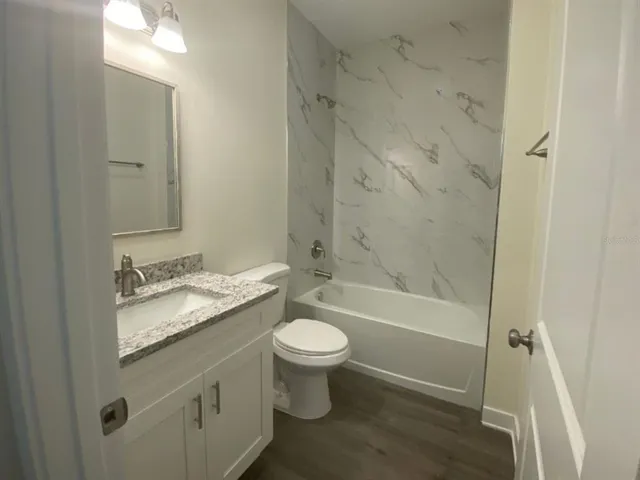 a bathroom with a granite countertop toilet a sink and a mirror