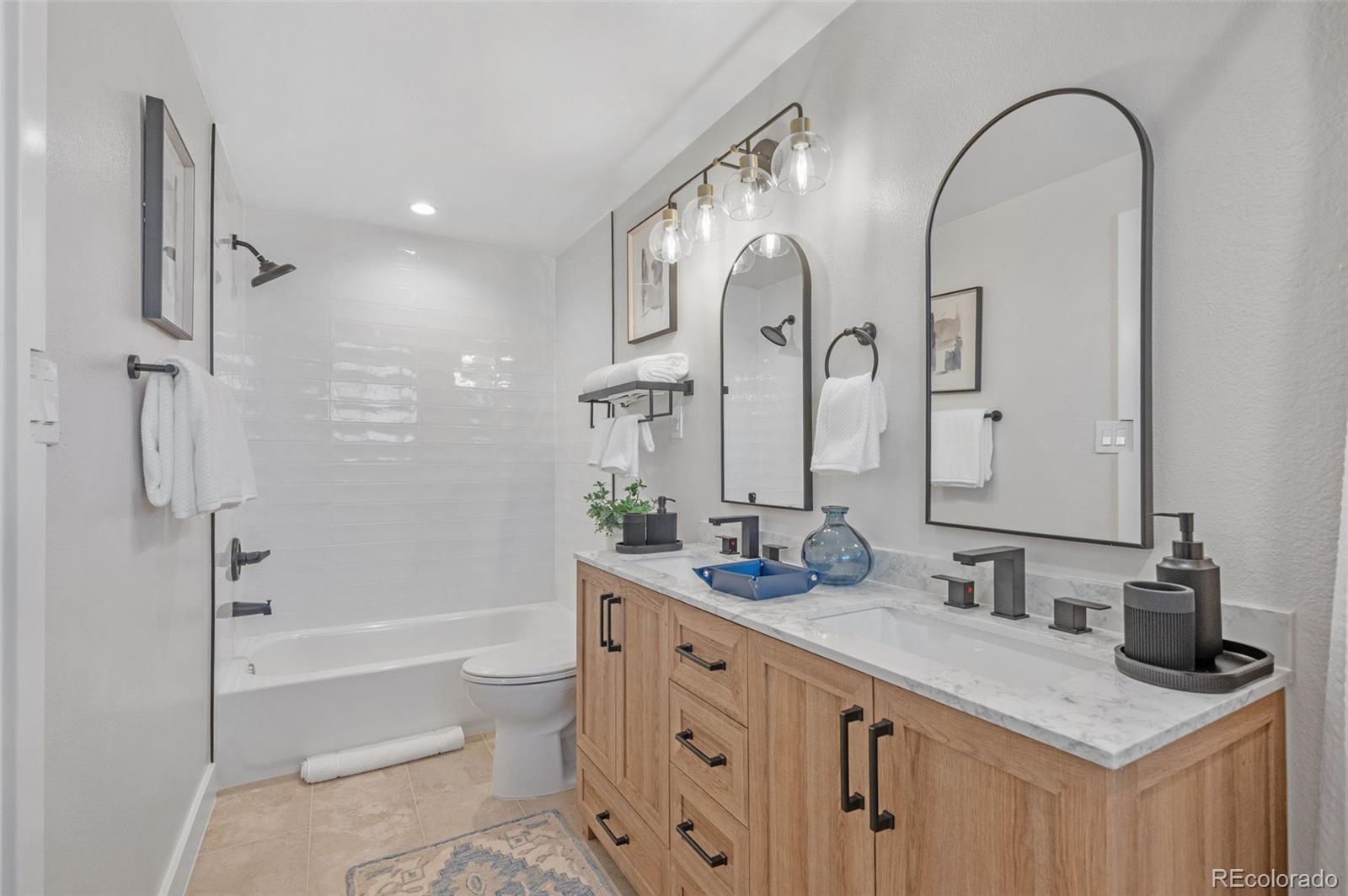 4481 Carr Street Wheat Ridge, CO 80033 - Photo 21 of 30 a spacious bathroom with a granite countertop sink mirror toilet and bathtub