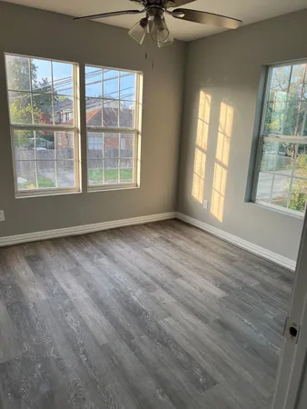 a view of an empty room with a window and wooden floor