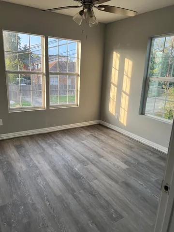 a view of an empty room with a window and wooden floor