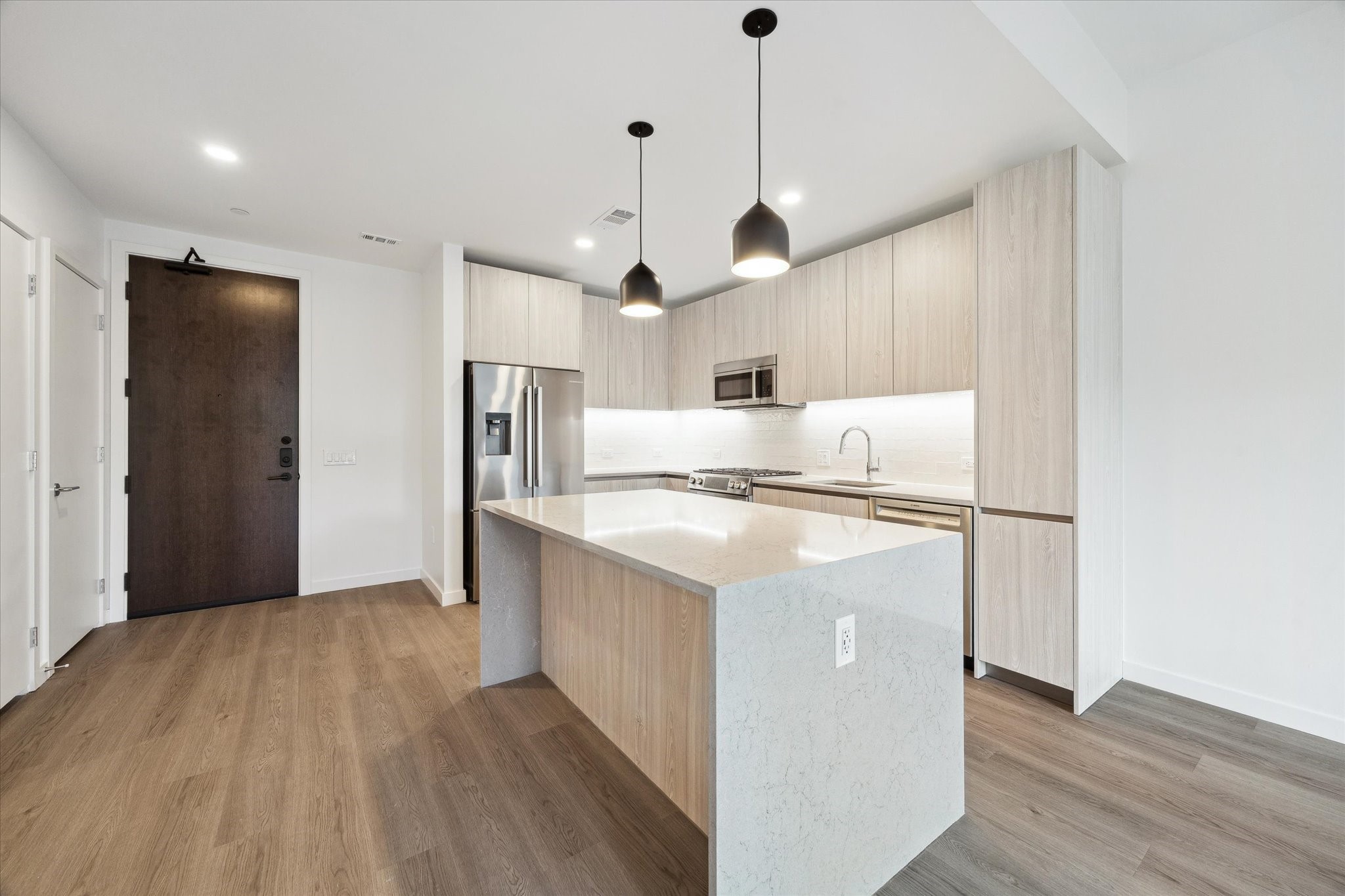 1 Riva Row, Unit 406 The Woodlands, TX 77380 - Photo 6 of 42 a kitchen with stainless steel appliances granite countertop a refrigerator a oven a sink dishwasher and a stove with wooden floor