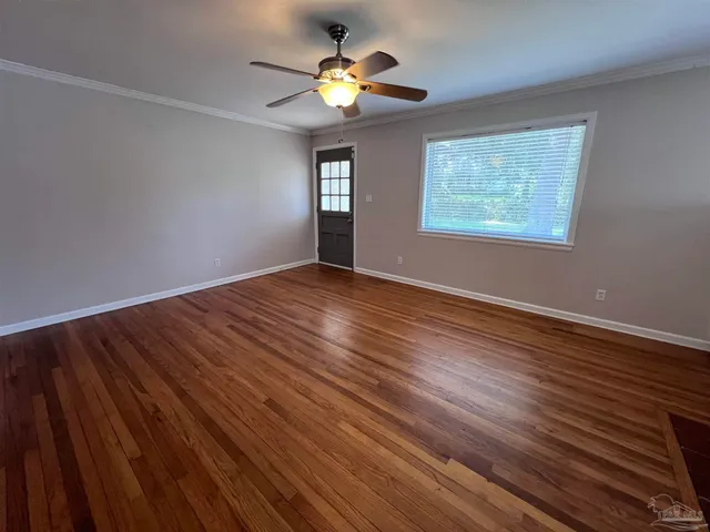 a view of an empty room with window and wooden floor