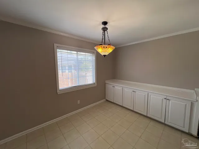 a view of an empty room with chandelier fan and window