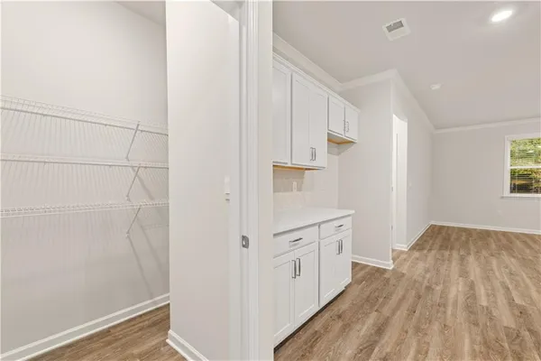 a kitchen with white cabinets and wooden floor