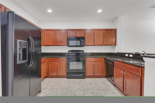 a kitchen with stainless steel appliances granite countertop a stove a sink and a refrigerator