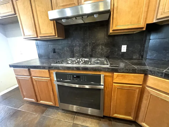 a kitchen with granite countertop wooden cabinets and a stove top oven