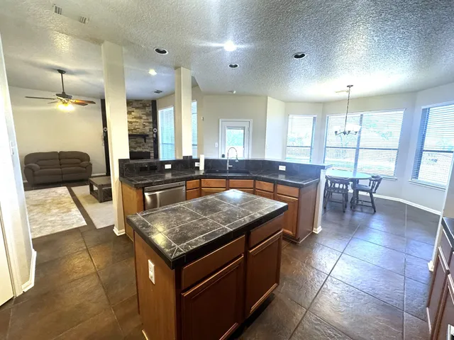 a kitchen with a stove a sink a counter top space and living room