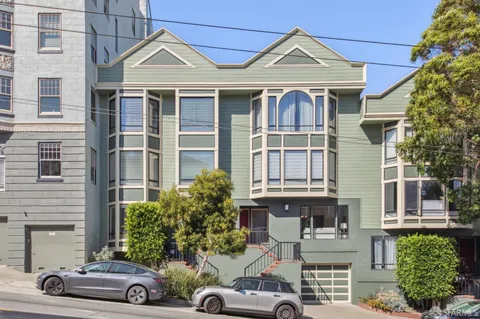 a view of a white house with large windows and a table and chairs