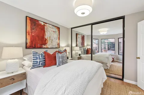 a bedroom with two beds and a large mirror next to a window