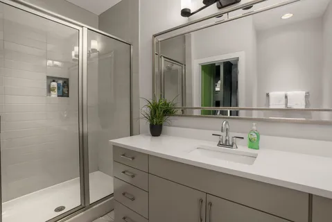 a view of a hallway with wooden floor and a bathroom