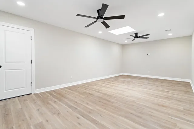 a view of empty room with wooden floor and ceiling fan