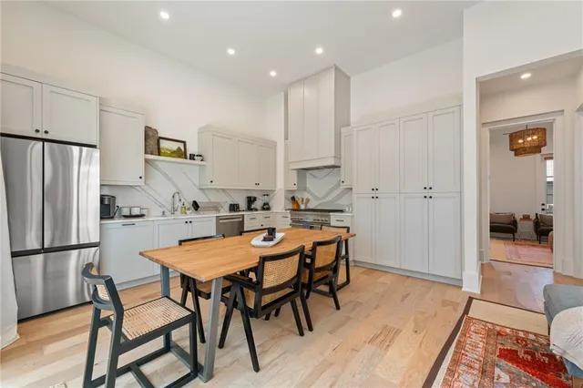 a kitchen with stainless steel appliances granite countertop a dining table chairs refrigerator and sink