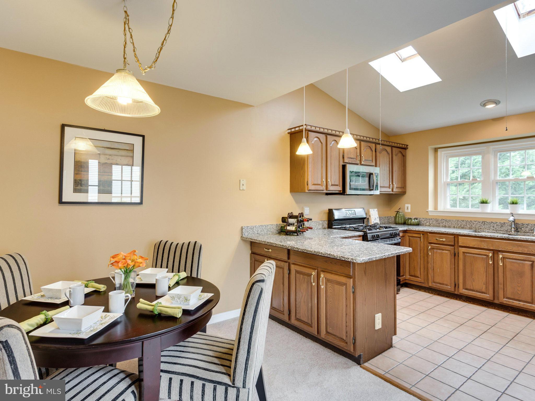 6564 Forsythia Street Springfield, VA 22150 - Photo 11 of 30 a kitchen with a stove a sink dishwasher and a dining table with garden view