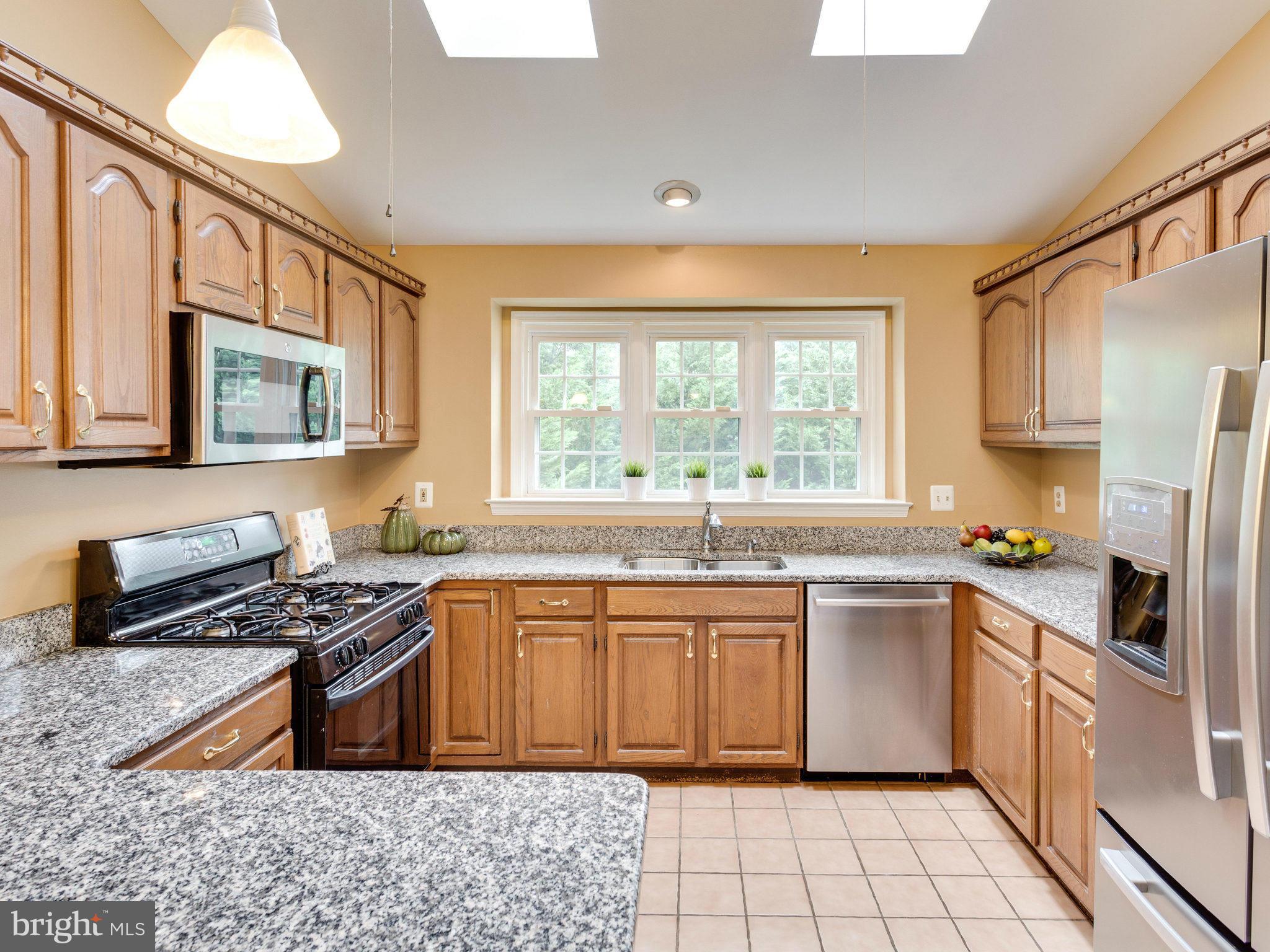 6564 Forsythia Street Springfield, VA 22150 - Photo 13 of 30 a kitchen with stainless steel appliances a stove sink microwave and cabinets