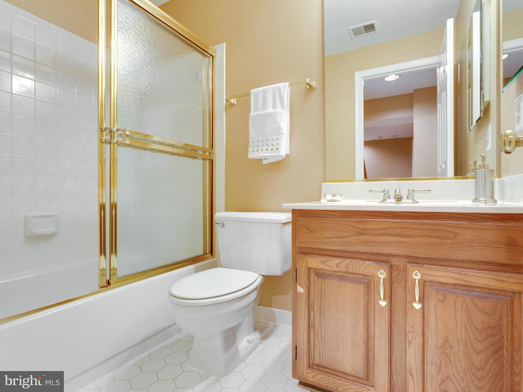 6564 Forsythia Street Springfield, VA 22150 - Photo 29 of 30 a bathroom with a granite countertop toilet sink and a mirror