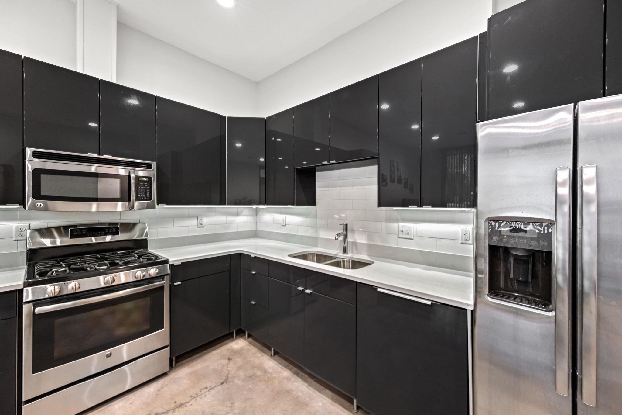 448 Tennessee Street Memphis, TN 38103 - Photo 30 of 39 Contemporary kitchen with gloss black cabinetry, stainless steel appliances, light countertops, and a white subway tile backsplash