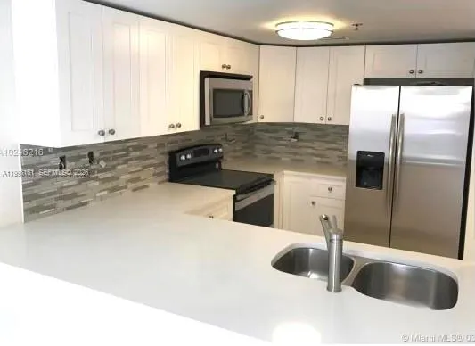 a kitchen with stainless steel appliances granite countertop a sink and a refrigerator