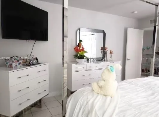 a bedroom with a bed a flat screen tv and view of bathroom