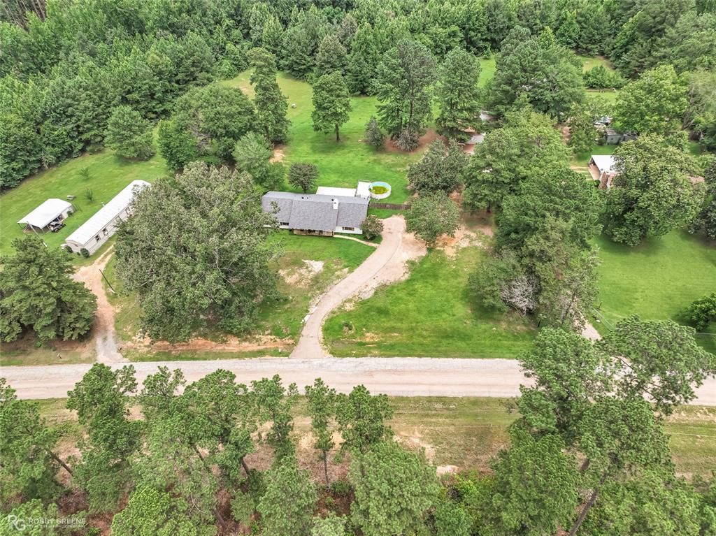 1426 Caney Lake Road Minden, LA 71055 - Photo 33 of 36 Expansive property featuring a central residence with a gray shingled roof, a winding gravel driveway, and substantial green space