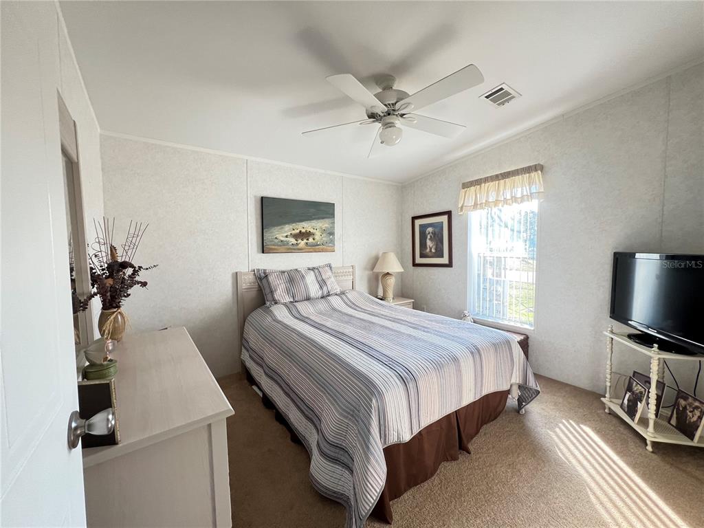 10100 Burnt Store Road, Unit 27 Punta Gorda, FL 33950 - Photo 26 of 37 a bedroom with a bed and a flat tv screen on dresser