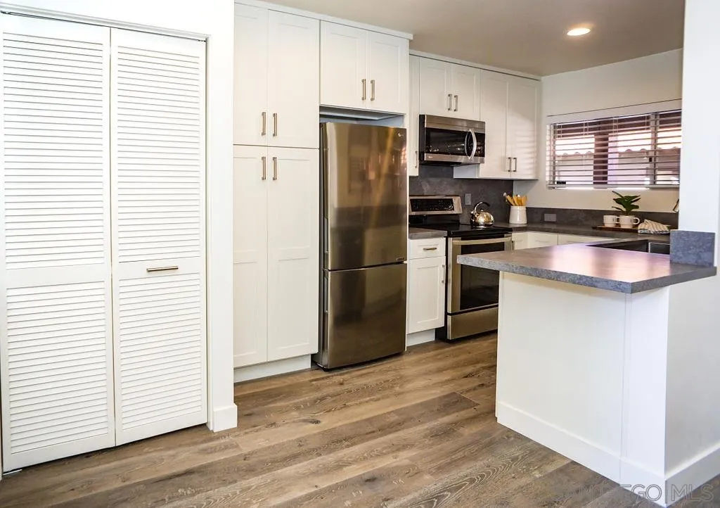 2630 Torrey Pines Road, Unit E22 La Jolla, CA 92037 - Photo 16 of 37 a kitchen with granite countertop a refrigerator and a stove