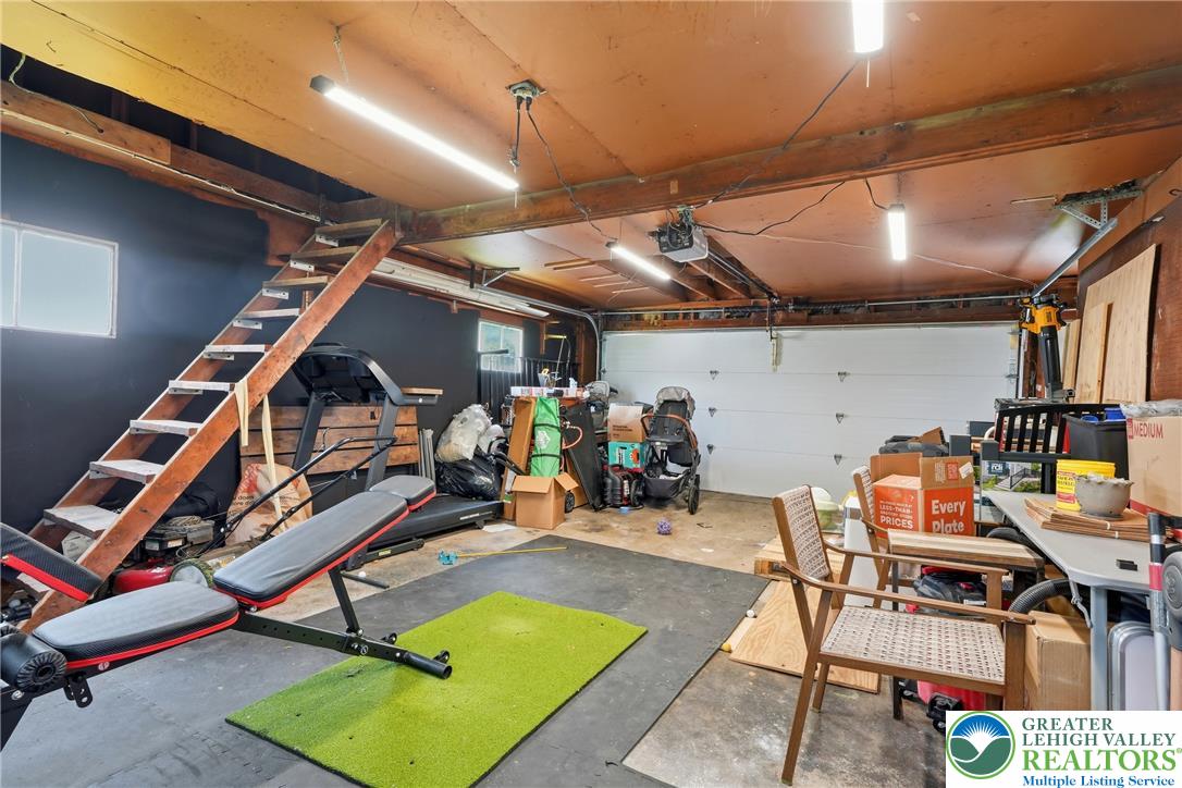 408 Maple Road Hellertown, PA 18055 - Photo 42 of 66 A spacious garage features concrete flooring, exposed overhead beams, and functional wooden stairs.